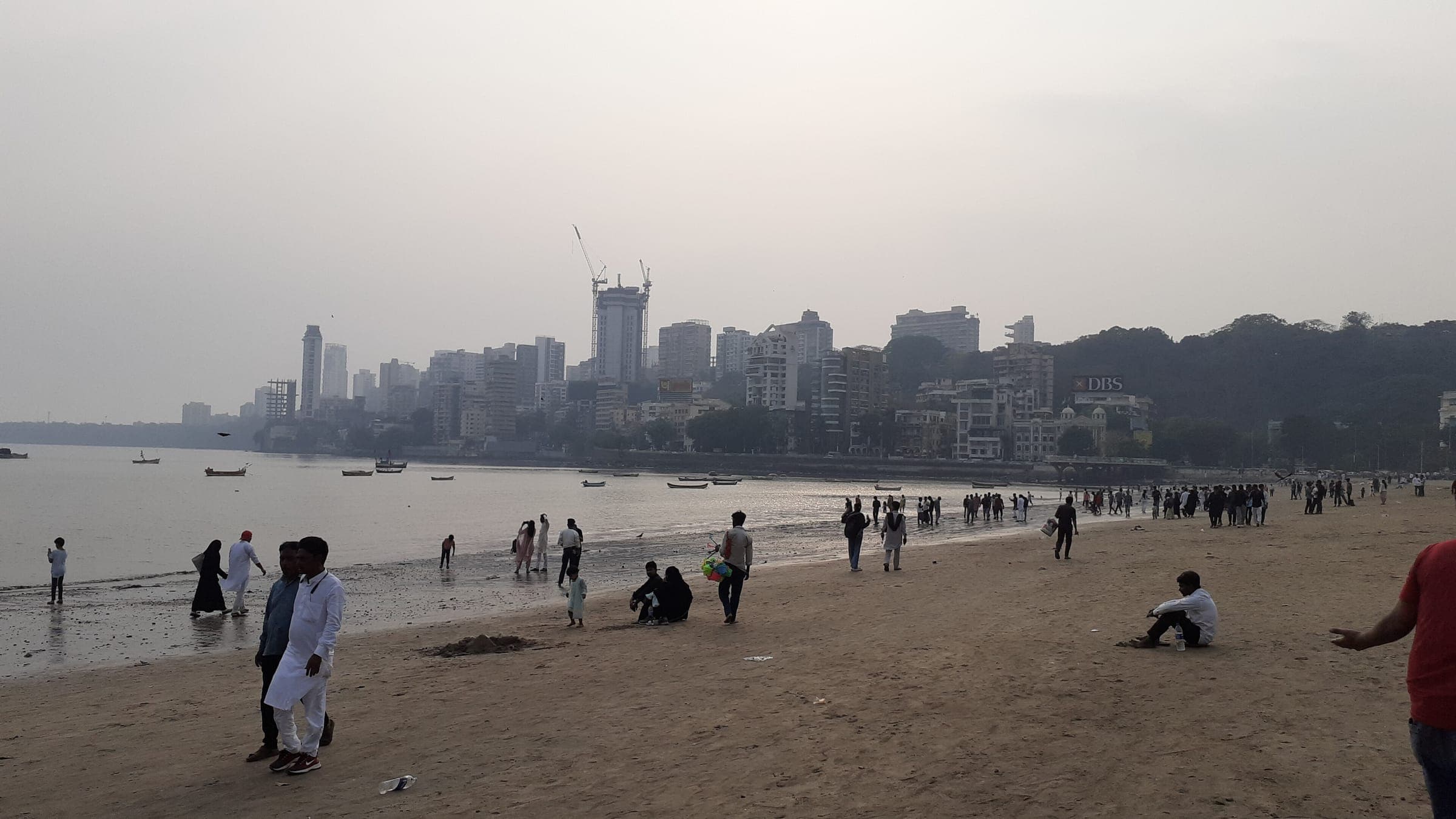 People walking on the sand at Girgaon Chowpatty, looking toward Malabar Hill
