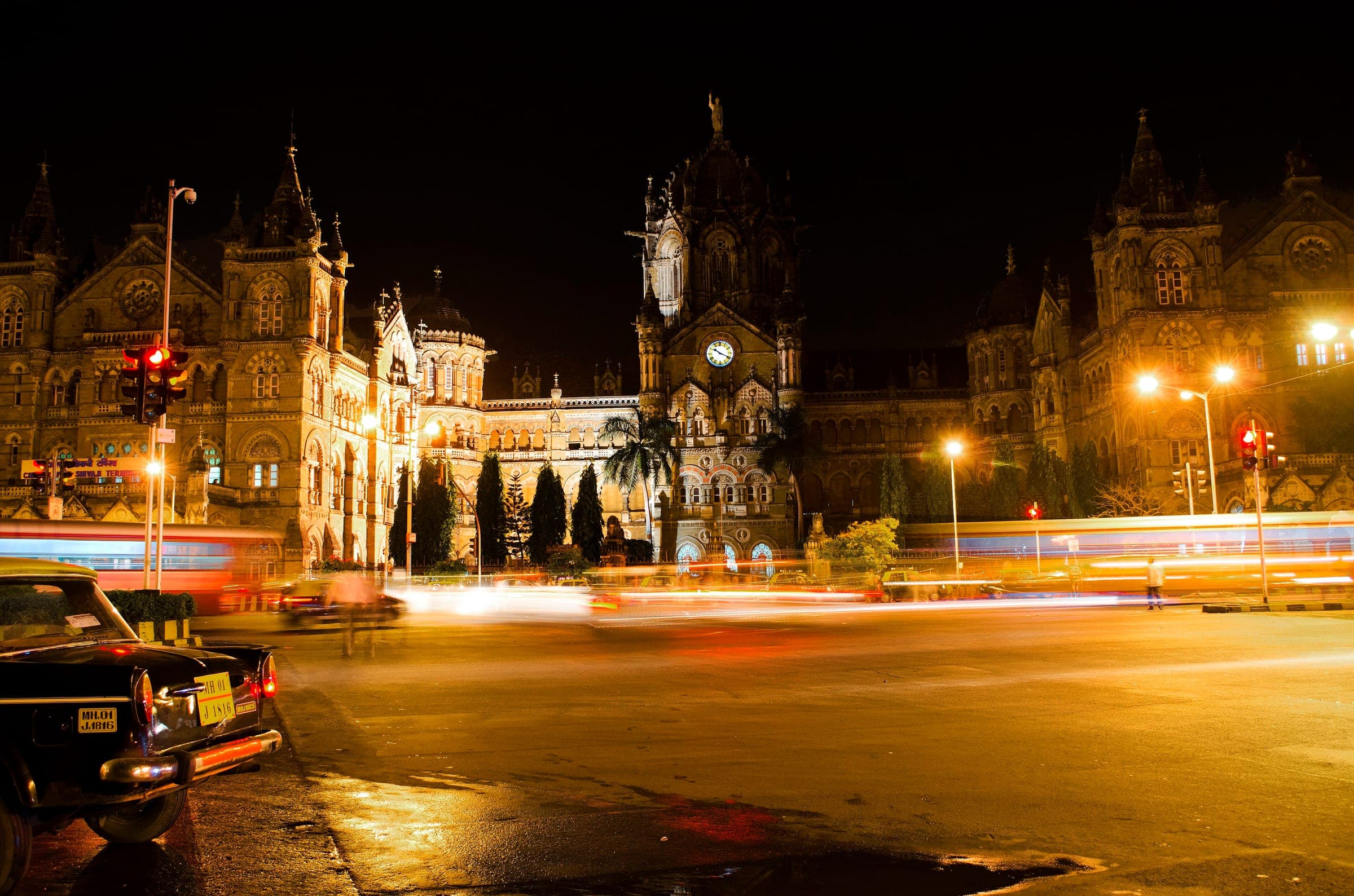 CSMT glowing at night with a kaali-peeli taxi parked in the foreground